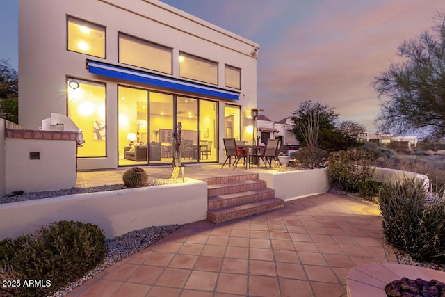 back house at dusk with a patio area