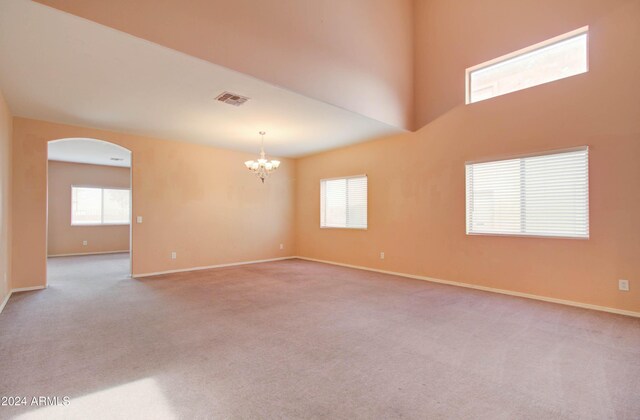 5659 S 239th Dr, Buckeye, AZ 85326 - carpeted empty room with arched walkways, an inviting chandelier, baseboards, and visible vents