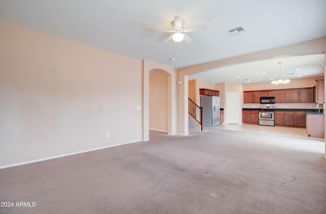 5659 S 239th Dr, Buckeye, AZ 85326 - unfurnished living room featuring baseboards, light carpet, visible vents, arched walkways, and ceiling fan with notable chandelier