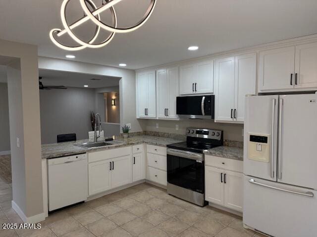 kitchen featuring stainless steel appliances, white cabinets, a sink, and light stone countertops