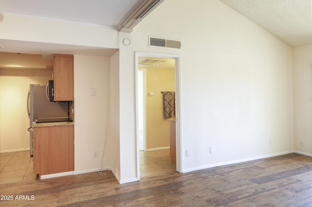 7350 N Via Paseo Del Sur Unit N207, Scottsdale, AZ 85258 - empty room featuring wood finished floors, vaulted ceiling, and baseboards