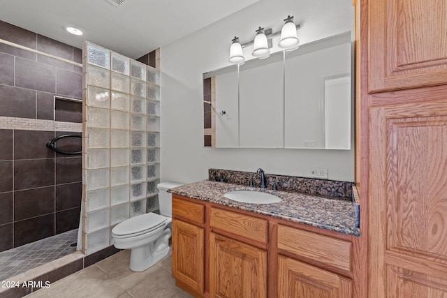 bathroom featuring a tile shower, vanity, toilet, and tile patterned floors