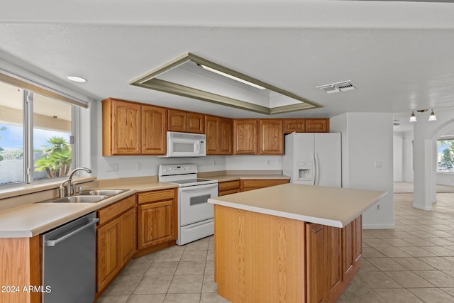 kitchen with light tile patterned flooring, sink, white appliances, and a kitchen island