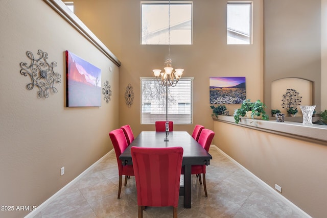 tiled dining space featuring a notable chandelier, a wealth of natural light, and a high ceiling