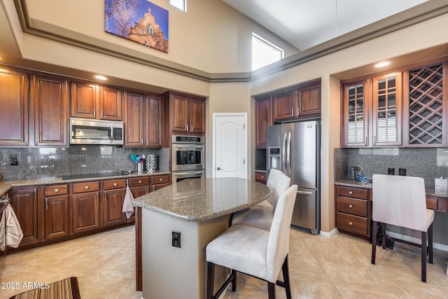 kitchen with stone countertops, a kitchen breakfast bar, a kitchen island, stainless steel appliances, and decorative backsplash