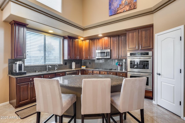 kitchen with sink, a breakfast bar area, dark stone counters, a center island, and stainless steel appliances