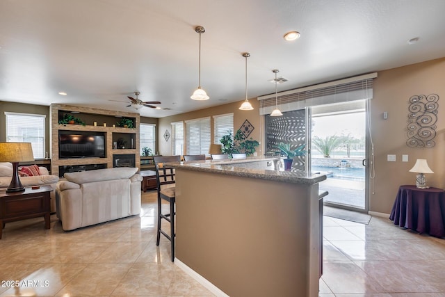 kitchen featuring decorative light fixtures, plenty of natural light, ceiling fan, and a kitchen bar