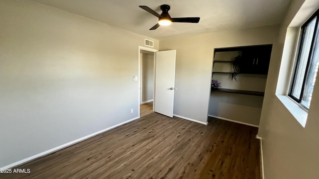 unfurnished bedroom with a closet, multiple windows, wood finished floors, and baseboards