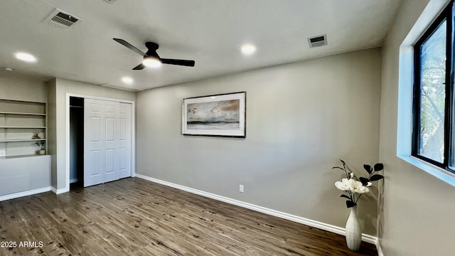 unfurnished bedroom featuring a ceiling fan, wood finished floors, visible vents, and baseboards