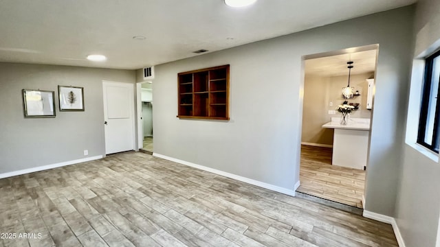 unfurnished room featuring visible vents, baseboards, and wood finished floors