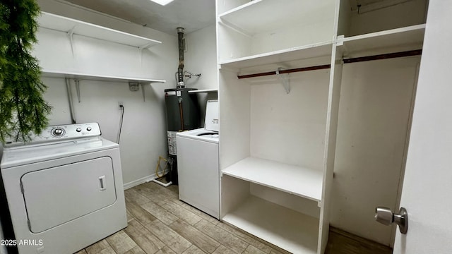 washroom with laundry area, washer and dryer, light wood finished floors, and gas water heater