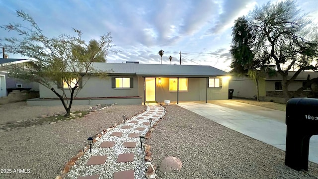 ranch-style house with concrete driveway and stucco siding