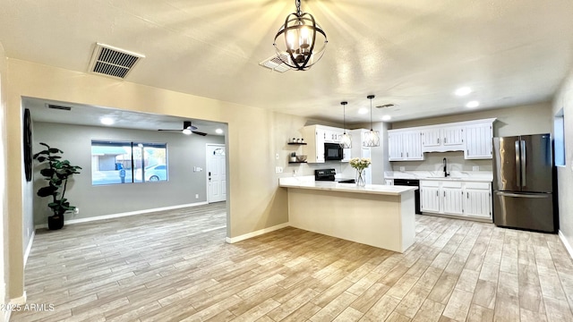 kitchen with a sink, visible vents, light wood-style floors, light countertops, and black appliances