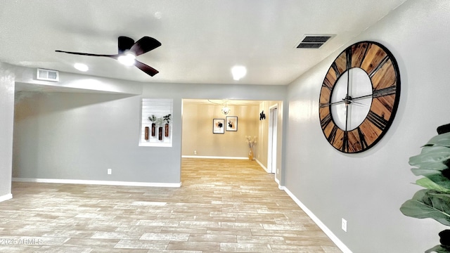 interior space featuring light wood-style flooring, visible vents, ceiling fan, and baseboards