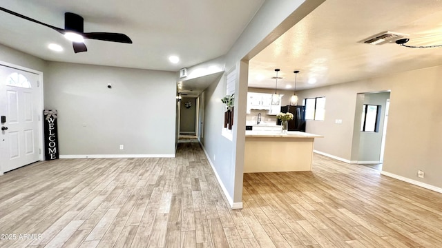 kitchen with pendant lighting, light countertops, freestanding refrigerator, white cabinets, and light wood-type flooring