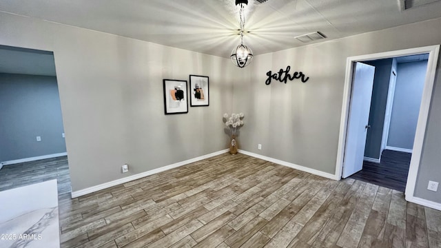 unfurnished dining area with baseboards, visible vents, and wood finished floors