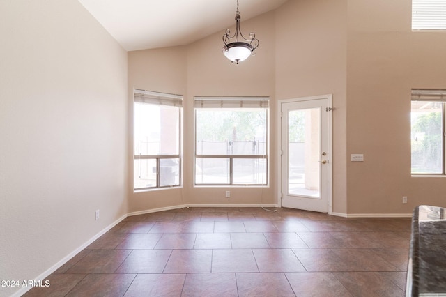 foyer entrance with high vaulted ceiling and dark tile patterned flooring