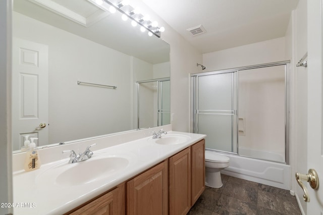 full bathroom featuring vanity, bath / shower combo with glass door, and toilet