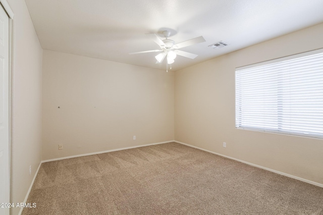 carpeted spare room featuring ceiling fan