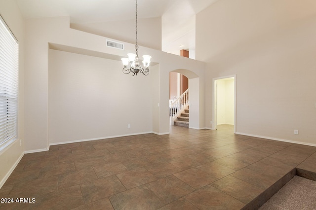 unfurnished room with high vaulted ceiling and a notable chandelier