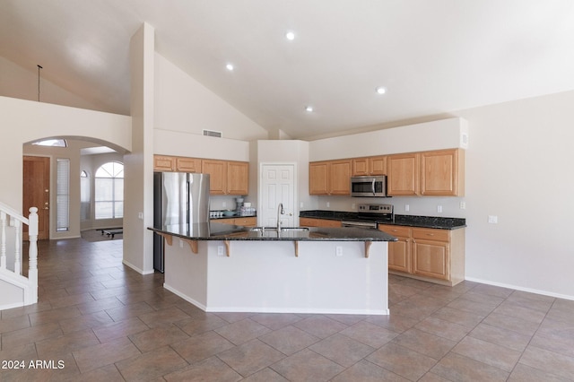 kitchen featuring appliances with stainless steel finishes, sink, a center island with sink, high vaulted ceiling, and a breakfast bar area