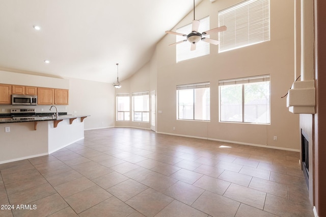 unfurnished living room with light tile patterned floors, high vaulted ceiling, ceiling fan, and sink