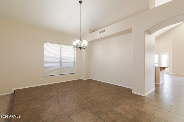 tiled empty room with plenty of natural light, high vaulted ceiling, and a notable chandelier