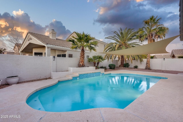 pool at dusk with a fenced backyard and a fenced in pool