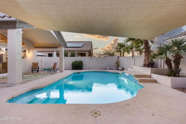 pool at dusk featuring a patio, a fenced backyard, and a fenced in pool