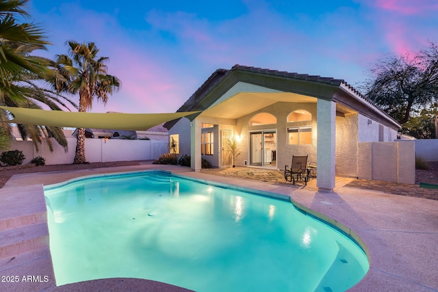 pool at dusk with a fenced backyard, a fenced in pool, and a patio