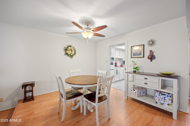 dining area with light wood-type flooring, ceiling fan, and baseboards