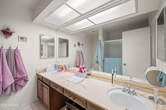 full bath featuring double vanity, tile patterned flooring, a sink, and a shower stall