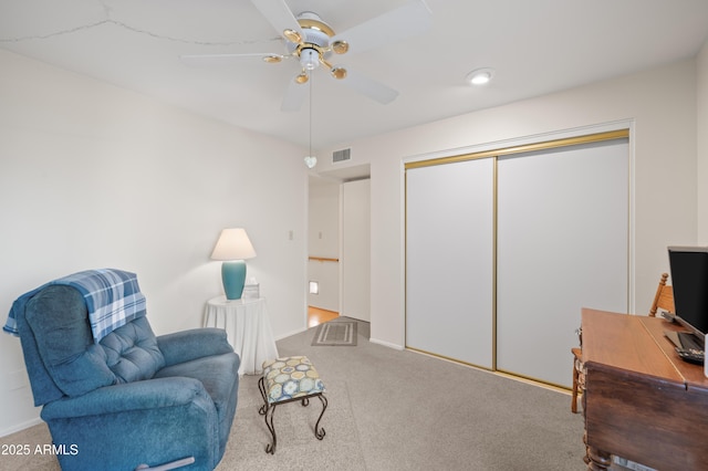 living area featuring carpet floors, visible vents, and a ceiling fan