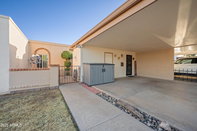 view of front of house featuring stucco siding, concrete driveway, a gate, fence, and a carport