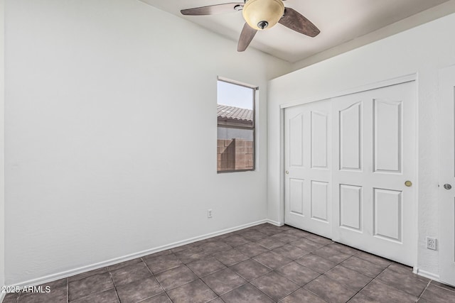26264 N 74th Ln, Peoria, AZ 85383 - unfurnished bedroom with a closet, a ceiling fan, dark tile patterned floors, and baseboards