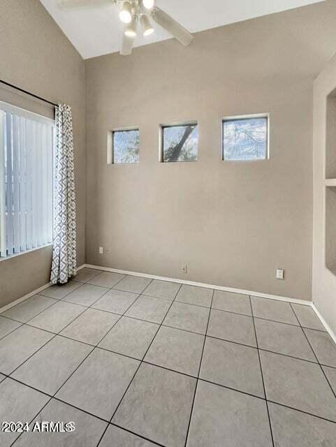 tiled spare room with vaulted ceiling and ceiling fan