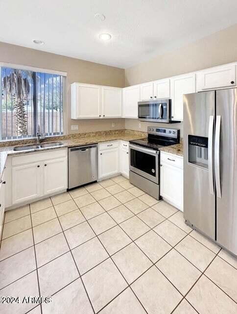 kitchen featuring white cabinets, light tile patterned flooring, appliances with stainless steel finishes, and sink