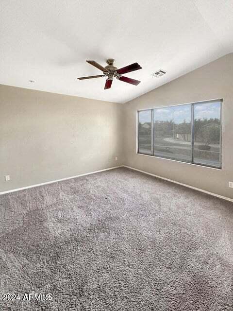 carpeted empty room with ceiling fan and vaulted ceiling