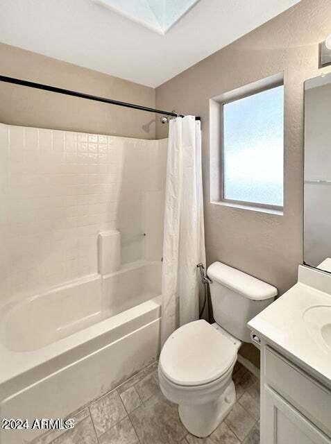 full bathroom with vanity, a skylight, shower / bath combination with curtain, and toilet