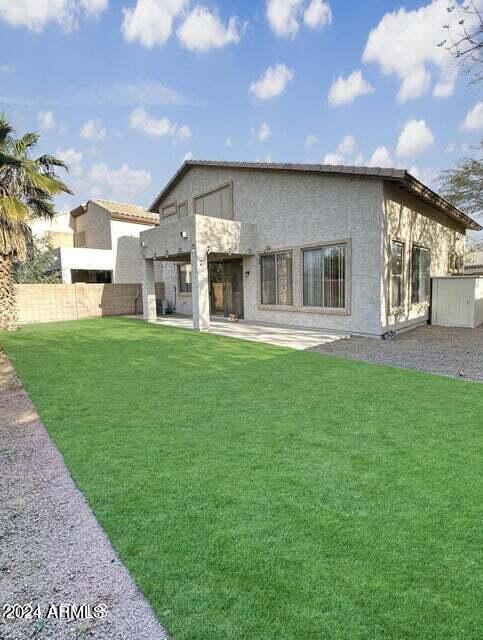 rear view of property featuring a balcony, a patio area, and a yard