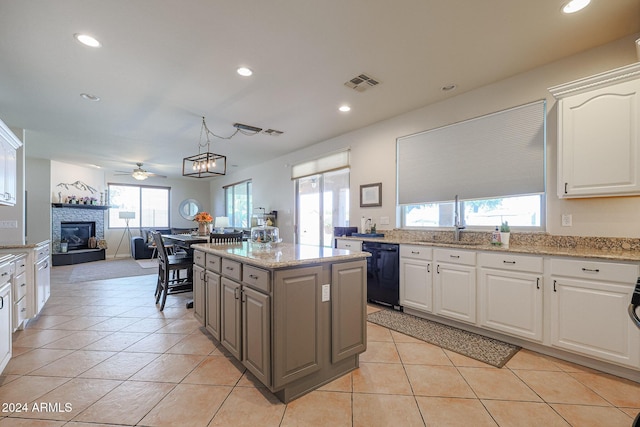14586 W Columbus Ave, Goodyear, AZ 85395 - kitchen with black dishwasher, a tile fireplace, a sink, a ceiling fan, and a kitchen island