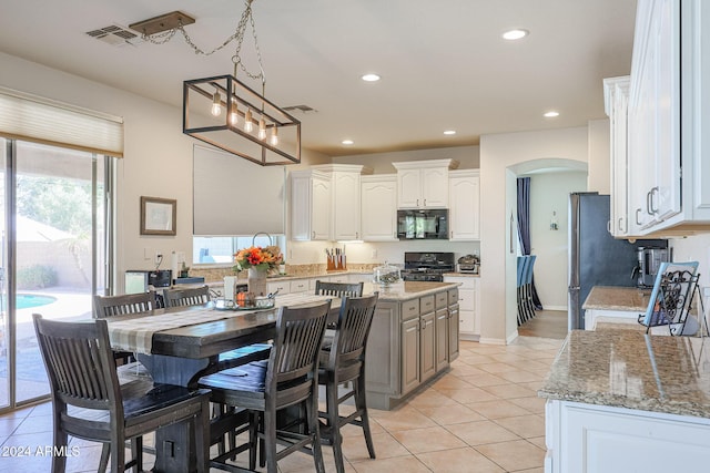 14586 W Columbus Ave, Goodyear, AZ 85395 - kitchen with black microwave, range with gas stovetop, arched walkways, light tile patterned floors, and white cabinetry