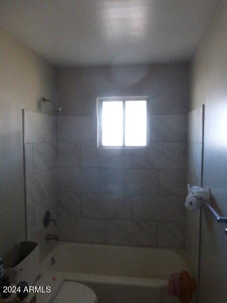 bathroom with tiled shower / bath combo and toilet