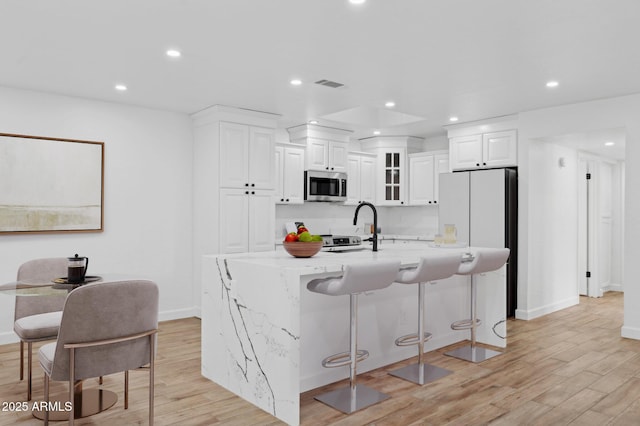 5756 N 78th Pl, Scottsdale, AZ 85250 - kitchen featuring stainless steel microwave, light wood-style flooring, baseboards, a breakfast bar, and recessed lighting