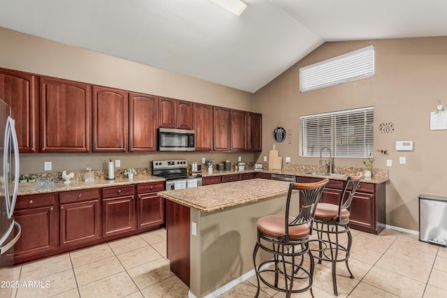 12376 W Hazelwood St, Avondale, AZ 85392 - kitchen featuring light stone counters, light tile patterned floors, a kitchen island, a breakfast bar area, and appliances with stainless steel finishes