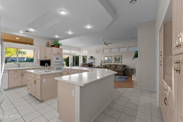 kitchen featuring light brown cabinetry, white appliances, ceiling fan, light tile patterned floors, and an island with sink