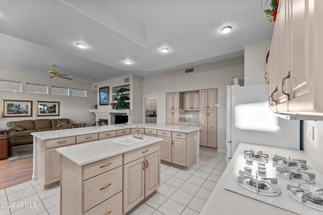 kitchen featuring white appliances, a kitchen island with sink, sink, ceiling fan, and light tile patterned floors