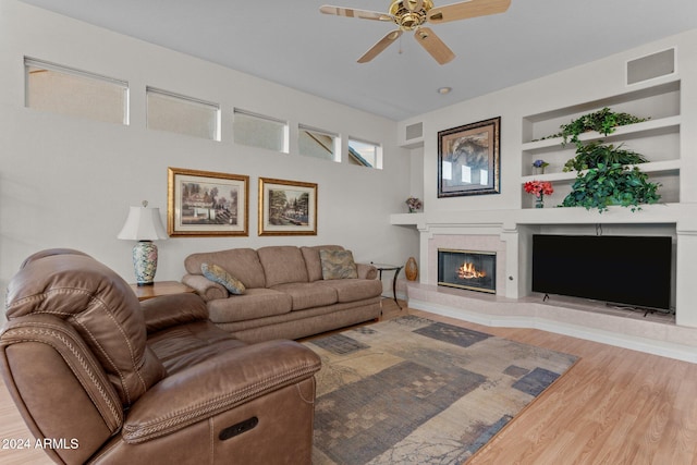 living room with a fireplace, hardwood / wood-style floors, built in features, and ceiling fan