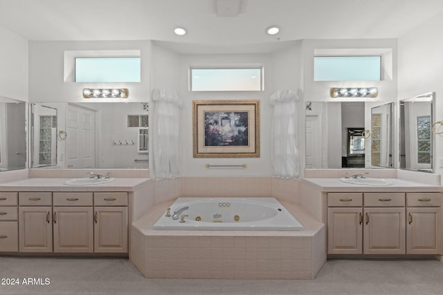 bathroom with tiled bath, plenty of natural light, and vanity