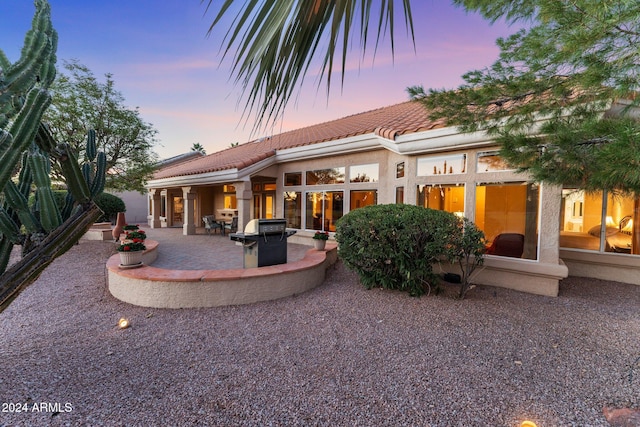 back house at dusk with a patio